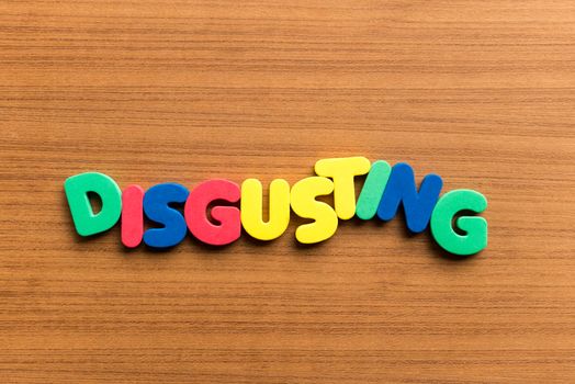 disgusting colorful word on the wooden background