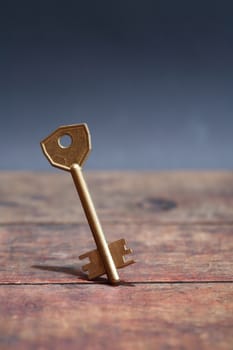 Door key standing on wooden board against dark background