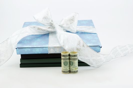 Gift wrapped book and lab notebooks placed with United States dollar currency reflects on wise investment in education and learning.  Savings through 529 and College Savings Plans through gifting.  Horizontal image with white background and copy space.