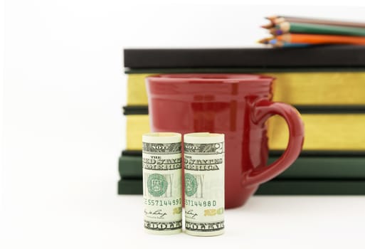 Careful accounting and investment work reflected in red mug, United States money, books, and pencils.  Selective focus on currency. White background with copy space.  