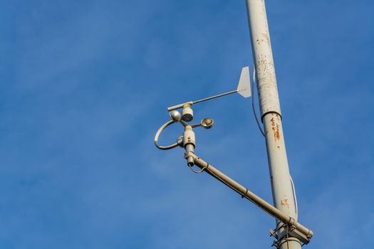Weather station with anemometer on blue sky.