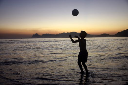 Playing soccer on the beach sunset