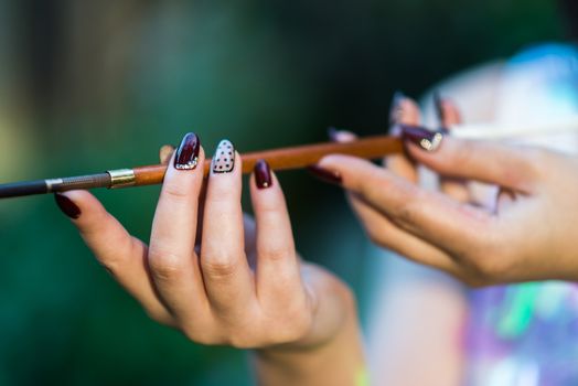 Beautiful hand of a young woman with brown manicure mouthpiece with cigarette