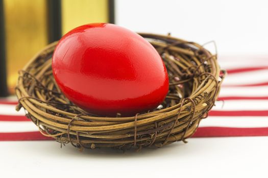 Red nest egg in front of books and red and white stripes of American flag.  