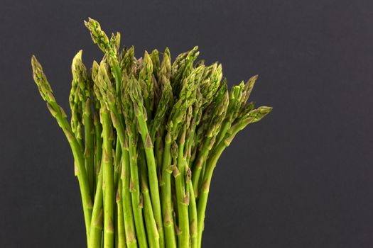 Fresh asparagus stalks in upright position agains black background. Horizontal image with copy space. 