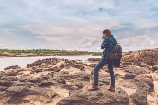  Asia woman taking a photo at Sampanbok natural stone park the grand-canyon of Ubonratchathani Thailand