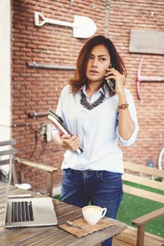 Asian woman talking on a cell phone at coffee shop.