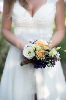 the bride holds a wedding bouquet with purple flowers