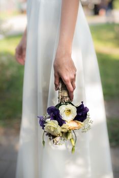 the bride holds a wedding bouquet with purple flowers