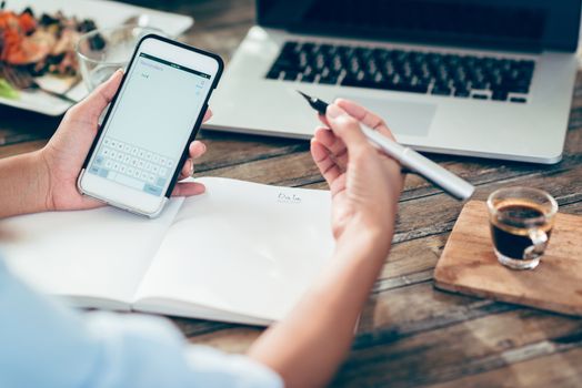 Photo Asian women are taking notes on paper, focus on Mobile