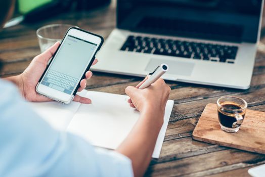 Woman taking notes on paper, focus on hands.