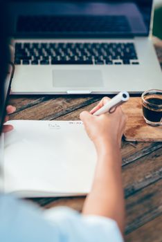 Woman taking notes on paper, focus on hands.