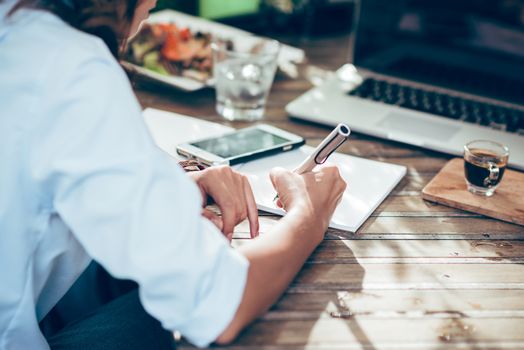 Woman taking notes on paper, focus on hands.