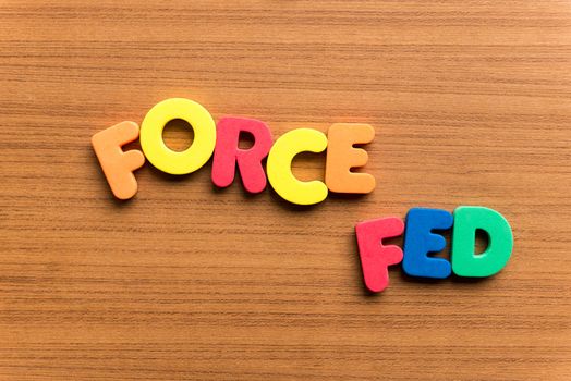 force fed colorful word on the wooden background