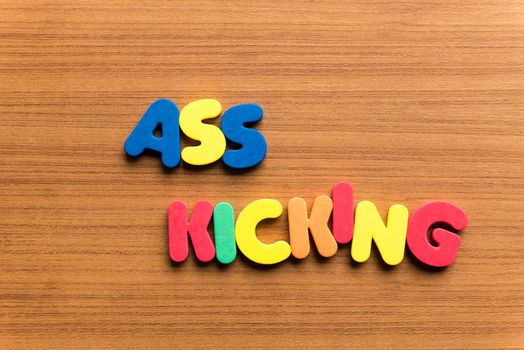 ass kicking colorful word on the wooden background