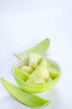 shopped green melon in bowl on white background