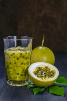 Fresh passion fruit juice in glass with passion fruits over wooden background , still life