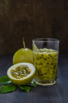 Fresh passion fruit juice in glass with passion fruits over wooden background , still life
