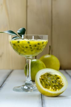 Fresh passion fruit juice in glass with passion fruits over wooden background , still life