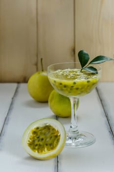 Fresh passion fruit juice in glass with passion fruits over wooden background , still life
