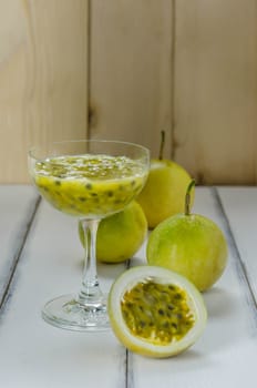 Fresh passion fruit juice in glass with passion fruits over wooden background , still life