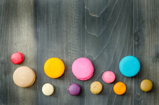 top view of colorful macaroons on a wooden background