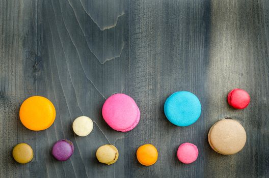 top view of colorful macaroons on a wooden background