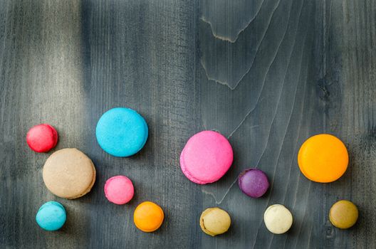 top view of colorful macaroons on a wooden background