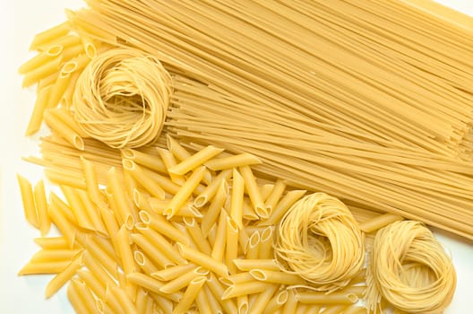 Different varieties of pasta, lay on a white surface. The view from the top.