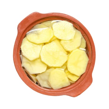 Sliced raw potatoes in the ceramic utensils for cooking. Isolated on a white background.