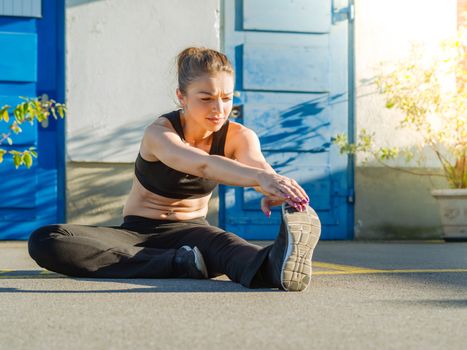 Photo of a fit young woman stretching her leg outside before a run late in the day.