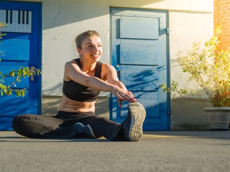 Photo of a toned young woman stretching her leg outside before a run late in the day.