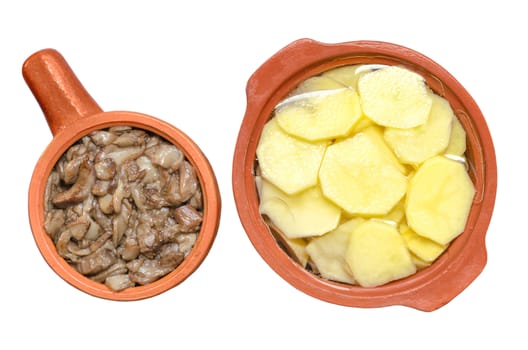 Sliced raw potatoes and sauteed mushrooms in ceramic dishes for cooking. Isolated on white background.