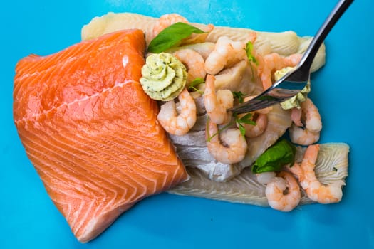 Various raw fish species as fillets like salmon, cod and shrimp.