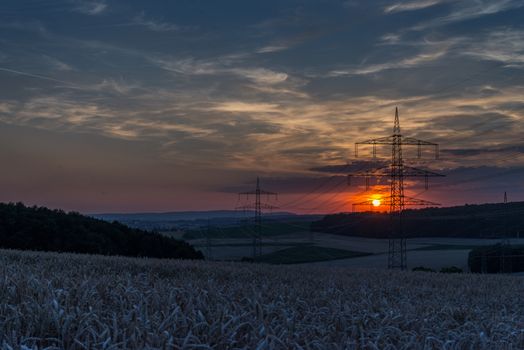 Sun setting behind the power lines.  farmers fields below.