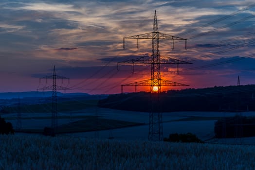 Sun setting behind the power lines.  farmers fields below.