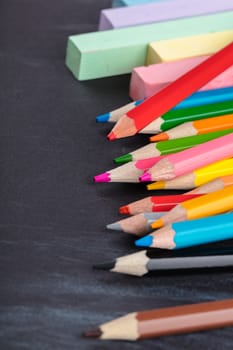 colored pencils and crayons on a black background