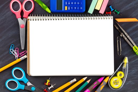 open notebook with stationery on black background