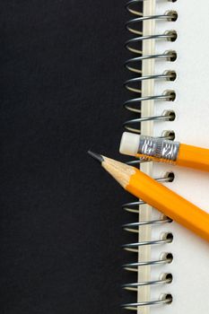 sharpened pencil and a notebook on black background