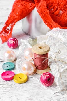 Fabric lace,bright colored buttons and thread on a light background