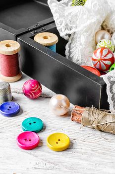 Fabric lace,bright colored buttons and thread on a light background