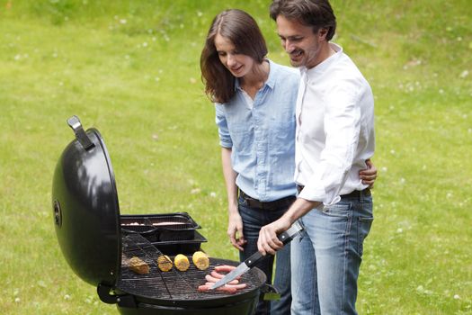 Happy couple cooking food on barbecue