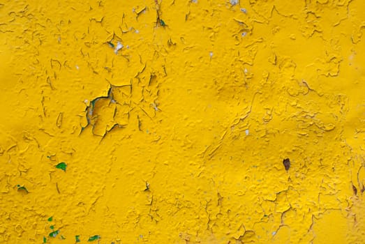 fragment of an iron surface is covered with yellow color paint, which has long been under the influence of different climatic conditions