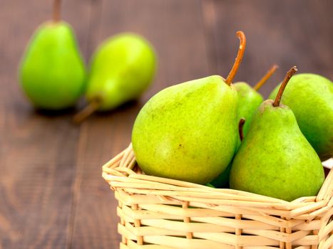 Healthy organic pears in basket on dark wooden background