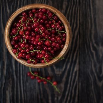 Fresh red currants in plate on wooden table