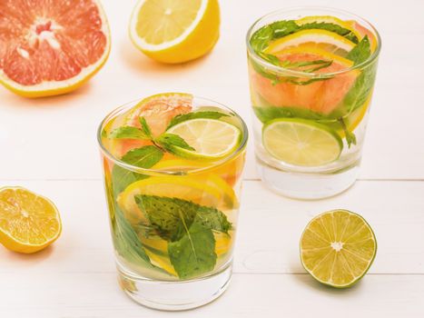 Cold homemade lemonade with fresh lemon, lime, grapefruit and mint. Summer drink on white wooden background