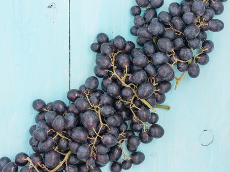 Purple grapes on soft blue wooden table with copyspace. Flat lay or top view