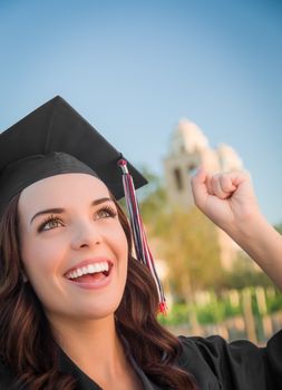 Happy Graduating Mixed Race Woman In Black Cap and Gown Celebrating on Campus.