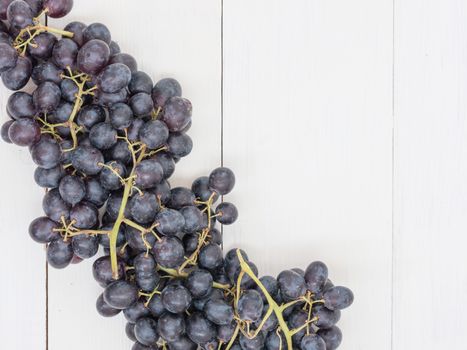 Purple grapes on white wooden table with copyspace. Flat lay or top view