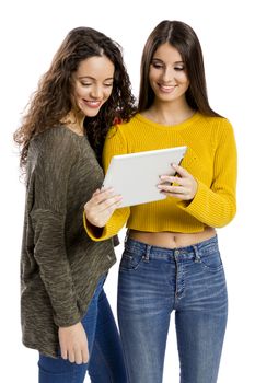 Studio portrait of two beautiful girls holding and showing something on a tablet